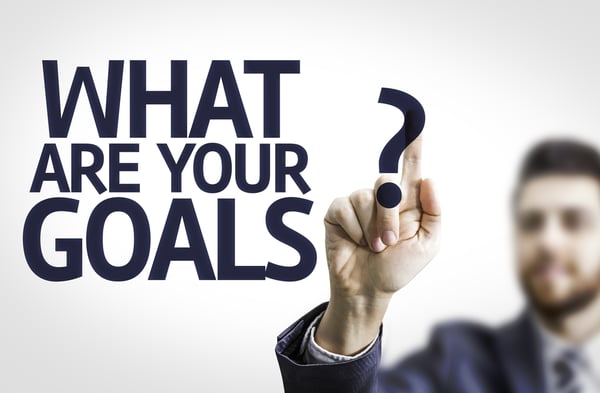 Business man pointing to transparent board with text What are Your Goals?-1