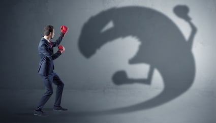 Businessman with boxing glove fighting with a big monster shadow