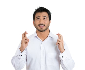 Closeup portrait of a young handsome man crossing fingers wishing and praying for miracle, hoping for the best, isolated on white background. Positive human emotion facial expression feelings attitude