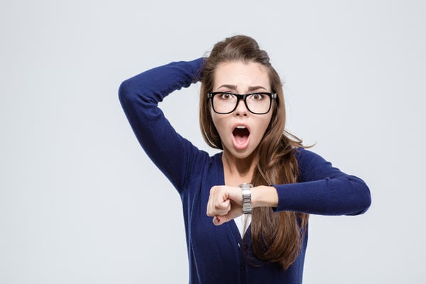 Portrait of shocked young woman holding hand with wrist watch and looking at camera isolated on a white background